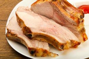 Roasted pork on the plate and wooden background photo