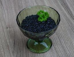 Black caviar in a bowl on wooden background photo