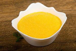 Raw polenta in a bowl on wooden background photo