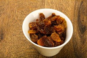 Dry Raisin in a bowl on wooden background photo