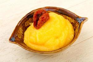 Polenta in a bowl on wooden background photo