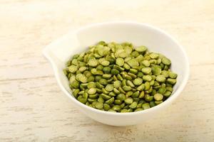 Green peas in a bowl on wooden background photo