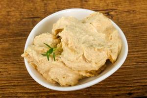 Humus in a bowl on wooden background photo