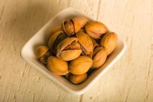 Pistachio in a bowl on wooden background photo