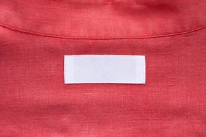 White blank clothing tag label on red linen shirt fabric texture background photo