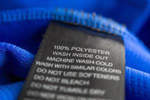 Black laundry care washing instructions clothes label on blue jersey polyester sport shirt photo