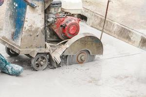 trabajador que utiliza una máquina de hoja de sierra de diamante cortando una carretera de hormigón en el sitio de construcción foto