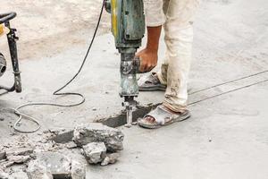 trabajador de la construcción con martillo perforador de superficie de hormigón foto