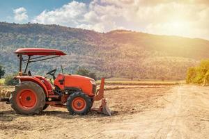 tractor in agriculture field with mountain and blue sky photo