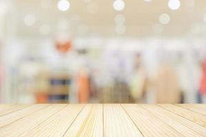 Empty wood table top with modern clothing store interior blur abstract defocused background with bokeh light for product display photo