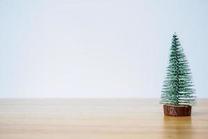 árbol de navidad en la mesa de madera con fondo de pared blanca foto