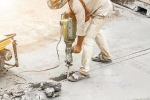 trabajador de la construcción con martillo perforador de superficie de hormigón foto