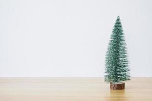 árbol de navidad en la mesa de madera con fondo de pared blanca foto