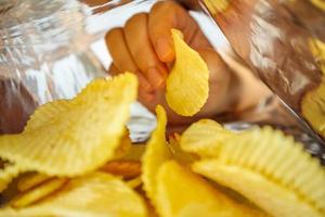 Hand hold potato chips inside snack foil bag photo