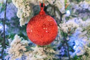 árbol de navidad decorado con bola roja sobre fondo de ramas de pino foto