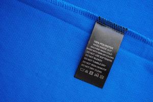 Black laundry care washing instructions clothes label on blue jersey polyester sport shirt photo