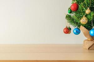 árbol de navidad en una mesa de madera decorada con bolas de colores en el fondo de ramas de pino foto