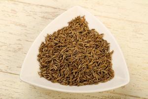 Cumin seeds in a bowl on wooden background photo