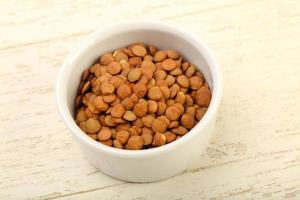 Raw lentils in a bowl on wooden background photo