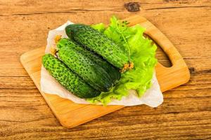 Green cucumbers on wooden board and wooden background photo