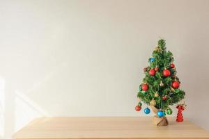 árbol de navidad en una mesa de madera decorada con bolas de colores en el fondo de ramas de pino foto