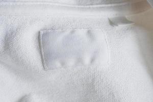 Blank white clothes label on new cotton shirt background photo