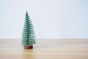 christmas tree on wood table with white wall background photo