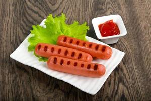 Grilled sausages on the plate and wooden background photo