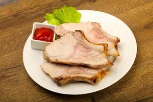 Roasted pork on the plate and wooden background photo