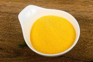 Raw polenta in a bowl on wooden background photo