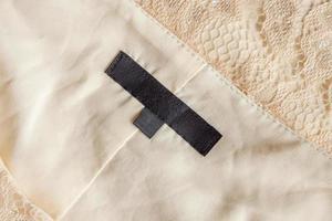 Blank black laundry care clothing label on fabric texture photo