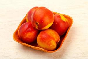 Nectarines in a bowl on wooden background photo