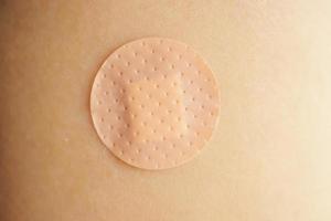 Close up circle brown adhesive bandage on patient arm after medicine injection or vaccination photo