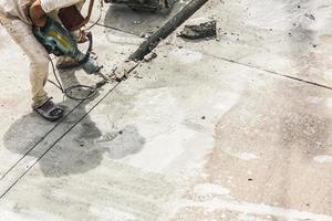 Construction worker using jackhammer drilling concrete surface photo