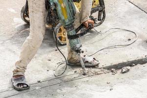 trabajador de la construcción con martillo perforador de superficie de hormigón foto