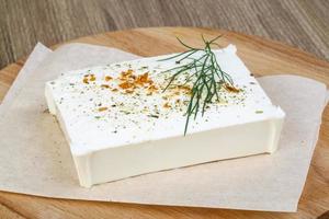 Feta cheese on wooden board and wooden background photo