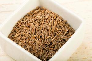 Cumin seeds in a bowl on wooden background photo