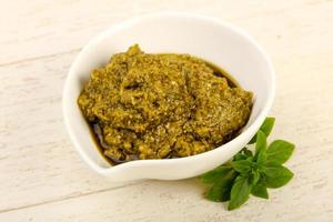 Pesto sauce in a bowl on wooden background photo