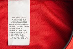 White laundry care washing instructions clothes label on red jersey polyester sport shirt photo