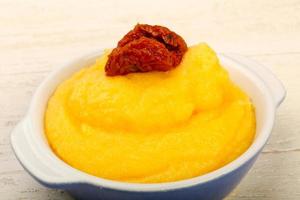 Polenta in a bowl on wooden background photo