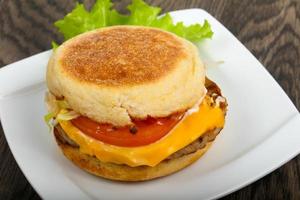 hamburguesa con queso en el plato y fondo de madera foto