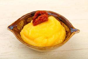 Polenta in a bowl on wooden background photo