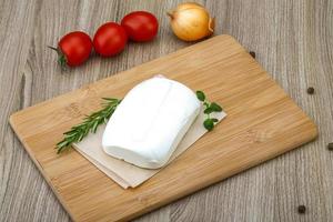 Feta cheese on wooden board and wooden background photo