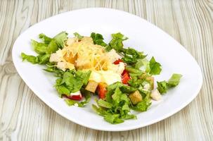 Caesar salad on the plate and wooden background photo