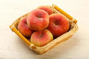 Sweet peaches in a basket on wooden background photo