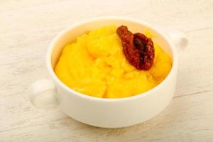 Polenta in a bowl on wooden background photo