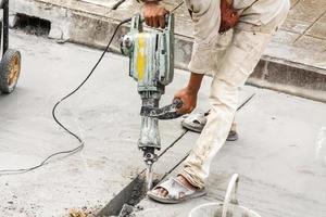 Construction worker using jackhammer drilling concrete surface photo