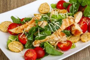 Caesar salad on the plate and wooden background photo