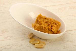 Peanut butter in a bowl on wooden background photo