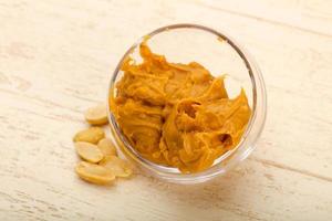 Peanut butter in a bowl on wooden background photo